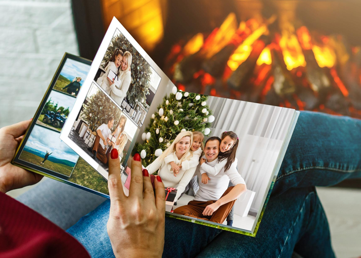Person holding open Bavens photo book by a warm fireplace